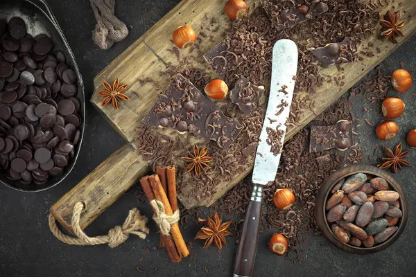 Kakao çekirdeğinin arka planında koyu çikolata ve mutfak malzemeleri.