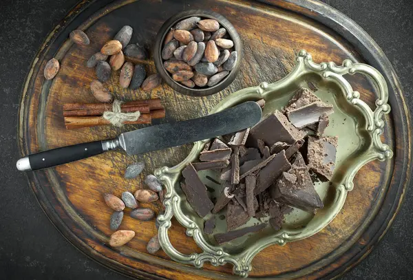 Kakao çekirdeğinin arka planında koyu çikolata ve mutfak malzemeleri.