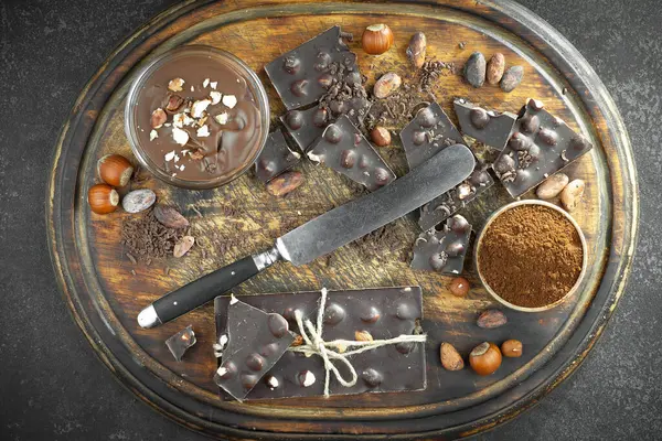 Kakao çekirdeğinin arka planında koyu çikolata ve mutfak malzemeleri.