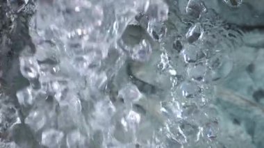 Bir su akıntısı yavaşça buzlu suya dökülür.