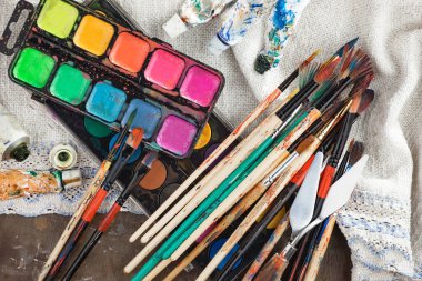 Eski bir arkaplanda resim yapmak için fırçalar ve boyalar.