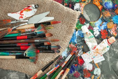 Eski bir arkaplanda resim yapmak için fırçalar ve boyalar.