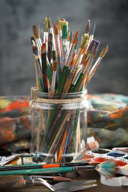 Eski bir arkaplanda resim yapmak için fırçalar ve boyalar.