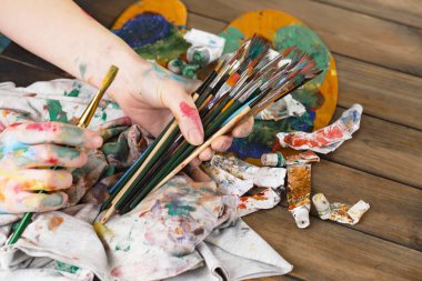 Sanatçının kadın elleri, çizim için fırçalar ve boyalar..