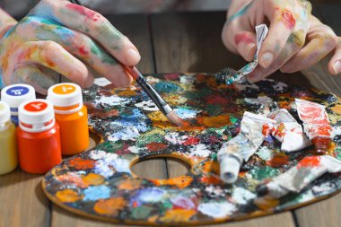 Sanatçının kadın elleri, çizim için fırçalar ve boyalar..