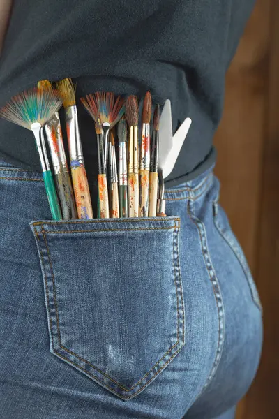 Female hands of the artist, with brushes and paints for drawing.