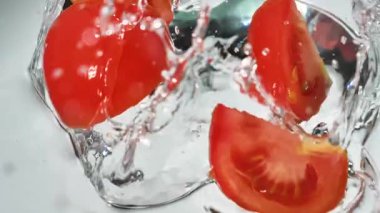 Kırmızı domatesler yavaşça büyük bir su akıntısıyla yıkanır.