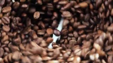 Kavrulmuş kahve çekirdekleri tahtada yavaşça zıplıyor.