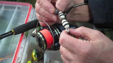 Stüdyo kompozisyonunda bir masada spor balıkçılık ekipmanları, bir ağın arka planına karşı. Balıkçının elleri, olta takımını kontrol eder..