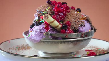 Metal bir kasede çikolatalı dondurma topları parlak renkli bir arka planda yavaşça döner..