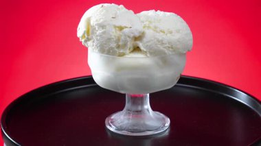 Cam kasedeki vanilyalı dondurma kadehleri parlak renkli arka planda yavaşça döner..