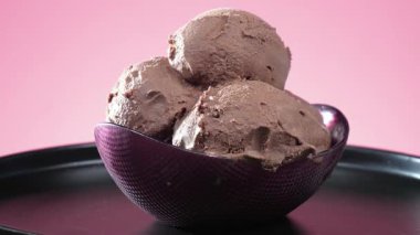 Çikolatalı dondurma topları parlak renkli bir arka planda yavaşça döner..