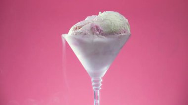 Bardaktaki vanilyalı dondurma kadehleri parlak renkli arka planda yavaşça dönüyor..