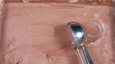 Çikolatalı dondurma topları yavaşça kaşığa konur ve konteynırdan çıkarılır..