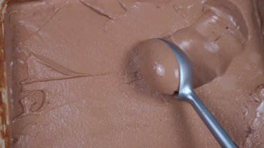 Çikolatalı dondurma topları yavaşça kaşığa konur ve konteynırdan çıkarılır..