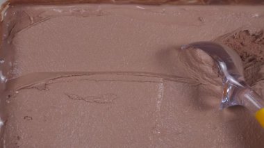 Çikolatalı dondurma topları yavaşça kaşığa konur ve konteynırdan çıkarılır..