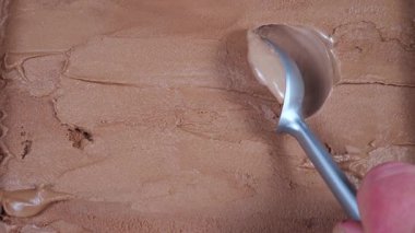 Çikolatalı dondurma topları yavaşça kaşığa konur ve konteynırdan çıkarılır..