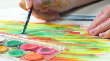 Sanatçının elleri, sanatta yaratıcı imgeler yaratmak için çalışır. Resim boyaları ve fırçalar, palet, guaj ve suluboya kullanarak tuvale çok renkli dokunuşlar uyguluyorlar..