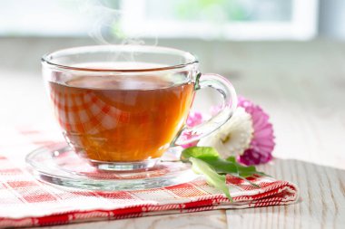 Bir fincan buharlı çay, hafif ahşap arka plan, masada aksesuarlarla kompozisyon..