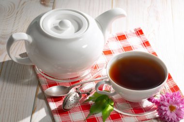 Bir fincan çaydanlıklı çay, arka planda, masada aksesuarlı bir kompozisyon.. 