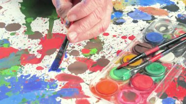 Bir sanatçı fırçaya suluboya boya uygular. Ellerine yakın çekim..