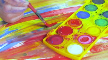 Bir sanatçı fırçaya suluboya boya uygular. Ellerine yakın çekim..