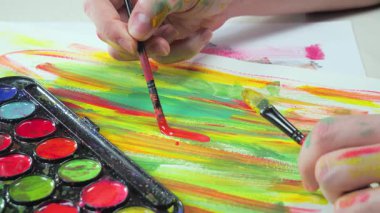 Bir sanatçı fırçaya suluboya boya uygular. Ellerine yakın çekim..