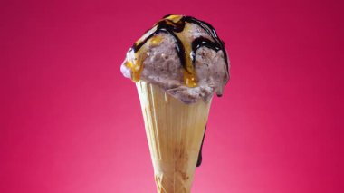 Parlak renkli arka planda waffle külahında çikolatalı dondurma, kendi ekseni etrafında yavaşça dönüyor..