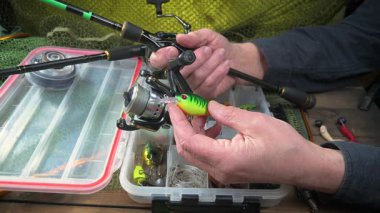 Bir balıkçı balık tutmadan önce takımlarını toplayıp kontrol eder. Ellerine yakın çekim..