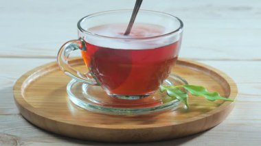 Hafif bir fincandaki siyah çay, hafif bir arka planda, kaşıkla karıştırılır..