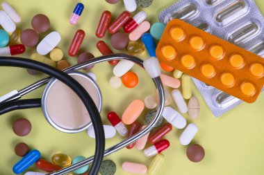 Haplar, termometre ve sarı arka planda steteskop. Üst görünüm.