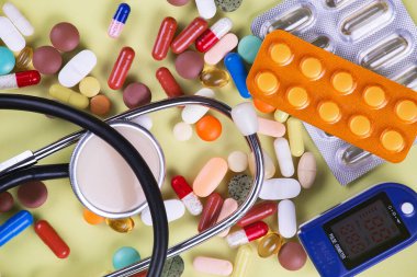 Haplar, termometre ve sarı arka planda steteskop. Üst görünüm.