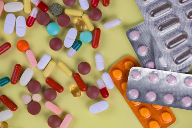 Haplar, termometre ve sarı arka planda steteskop. Üst görünüm.