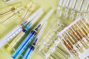 Sarı arka planda enjeksiyon ampulleri ve şırıngalar. Üst görünüm.