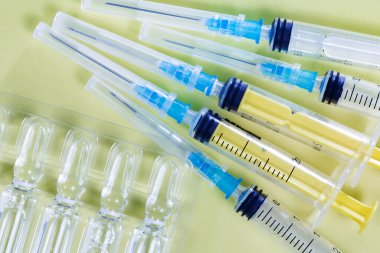 Sarı arka planda enjeksiyon ampulleri ve şırıngalar. Üst görünüm.