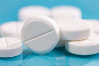 Masaya saçılmış beyaz yuvarlak tabletler, yeşil bir zemin üzerine.