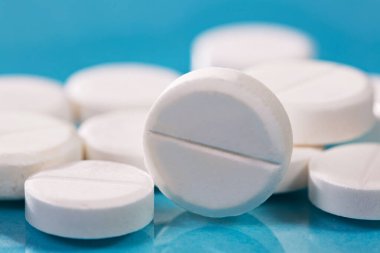 Masaya saçılmış beyaz yuvarlak tabletler, yeşil bir zemin üzerine.