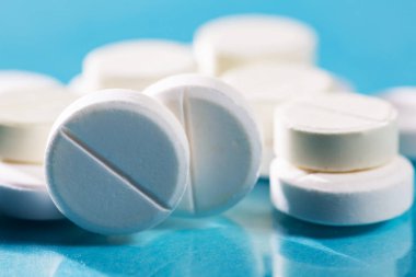 Masaya saçılmış beyaz yuvarlak tabletler, yeşil bir zemin üzerine.