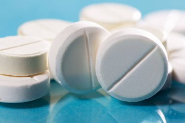 Masaya saçılmış beyaz yuvarlak tabletler, yeşil bir zemin üzerine.