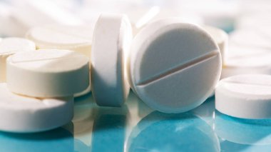 Masaya saçılmış beyaz yuvarlak tabletler, yeşil bir zemin üzerine.