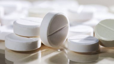 Masaya saçılmış beyaz yuvarlak tabletler, yeşil bir zemin üzerine.