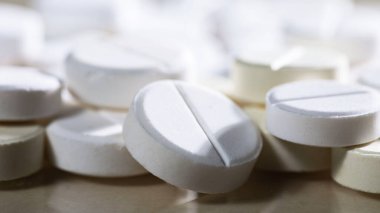 Masaya saçılmış beyaz yuvarlak tabletler, yeşil bir zemin üzerine.