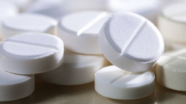 Masaya saçılmış beyaz yuvarlak tabletler, yeşil bir zemin üzerine.