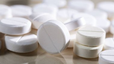 Masaya saçılmış beyaz yuvarlak tabletler, yeşil bir zemin üzerine.