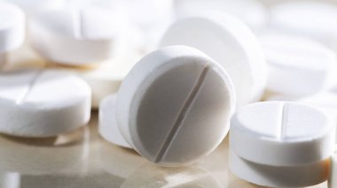 Masaya saçılmış beyaz yuvarlak tabletler, yeşil bir zemin üzerine.