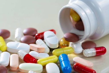 Kapsüllerdeki renkli tabletler kutudan masaya döküldü..