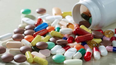 Kapsüllerdeki renkli tabletler kutudan masaya döküldü..