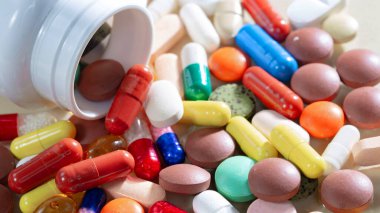 Kapsüllerdeki renkli tabletler kutudan masaya döküldü..