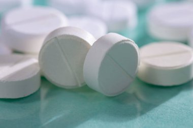 Masaya saçılmış beyaz yuvarlak tabletler, yeşil bir zemin üzerine.