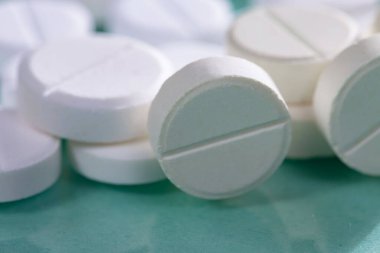 Masaya saçılmış beyaz yuvarlak tabletler, yeşil bir zemin üzerine.